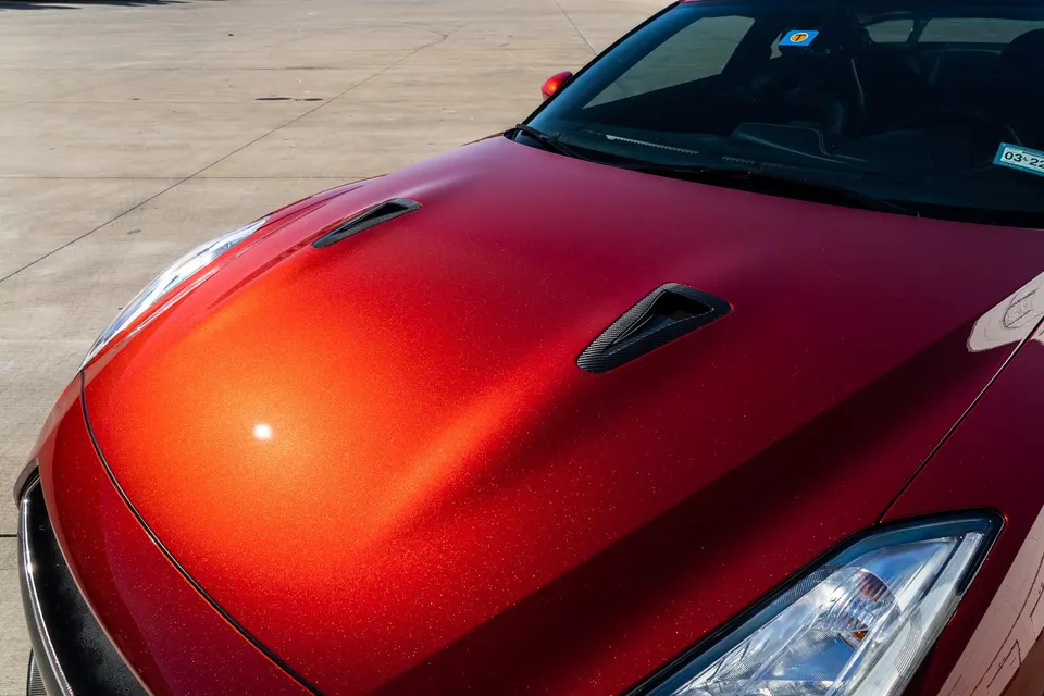 Close-up of a red Nissan GT-R's hood with carbon fiber vents and metallic paint finish.