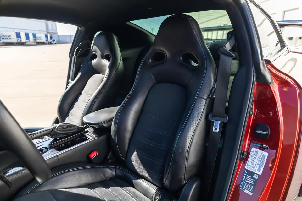 Interior view of a Nissan GT-R showing black leather racing seats, center console, and open door.