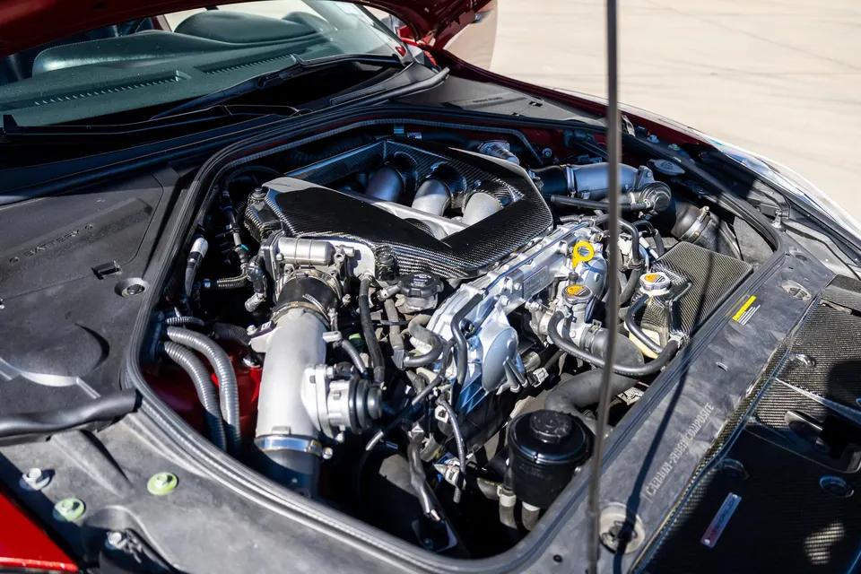 A close-up view of a Nissan GT-R VR38DETT engine bay featuring a carbon fiber intake manifold and performance upgrades.