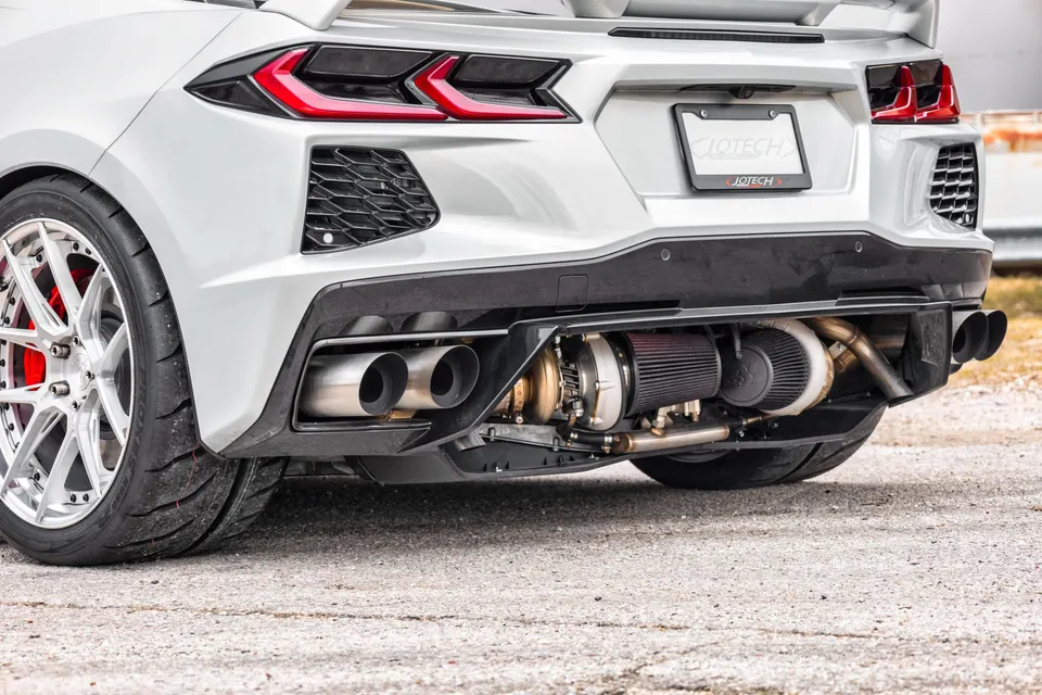 Rear view of a white Corvette C8 showcasing a custom twin-turbo setup with exposed turbochargers and exhaust.