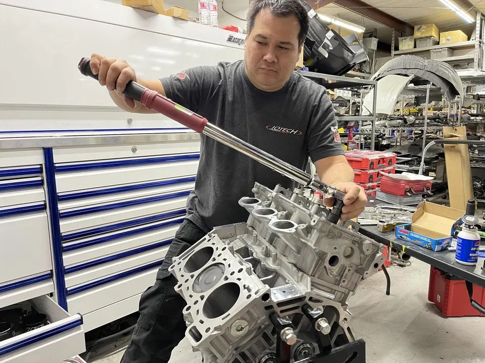 A Jotech Motorsports mechanic uses a torque wrench to assemble an engine block in the shop.