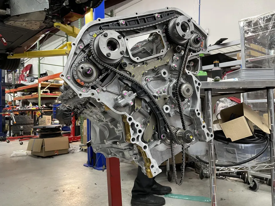 Engine block with timing chains and gears exposed during assembly in a performance tuning shop.