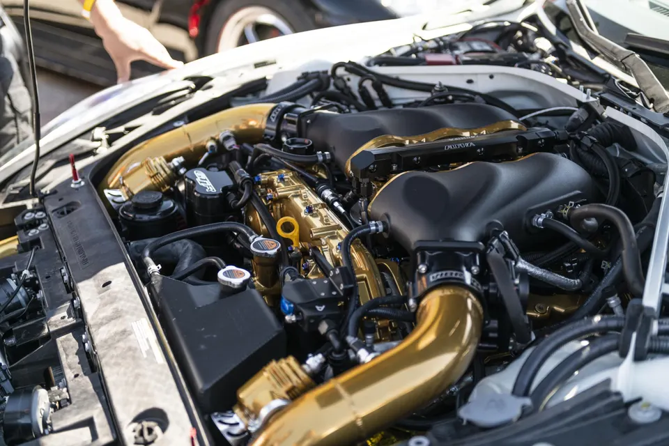 Close-up of a highly modified engine bay with gold intake piping and fuel rails.