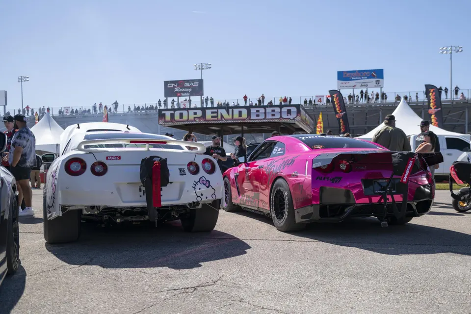 Two highly modified Nissan GT-R R35s, one white with Hello Kitty decals and one pink, at a drag racing event.
