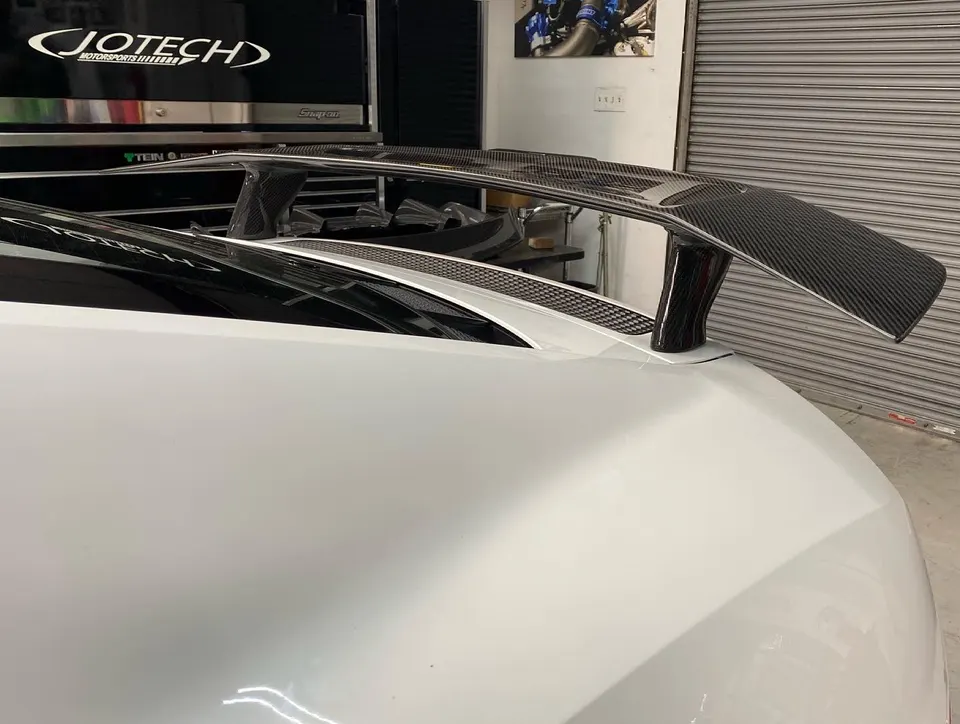 White car with a large carbon fiber rear wing installed at Jotech Motorsports shop.