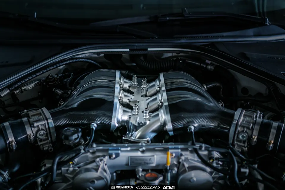 Close-up of a Jotech-tuned GT-R engine bay featuring a custom carbon fiber intake manifold and polished components.