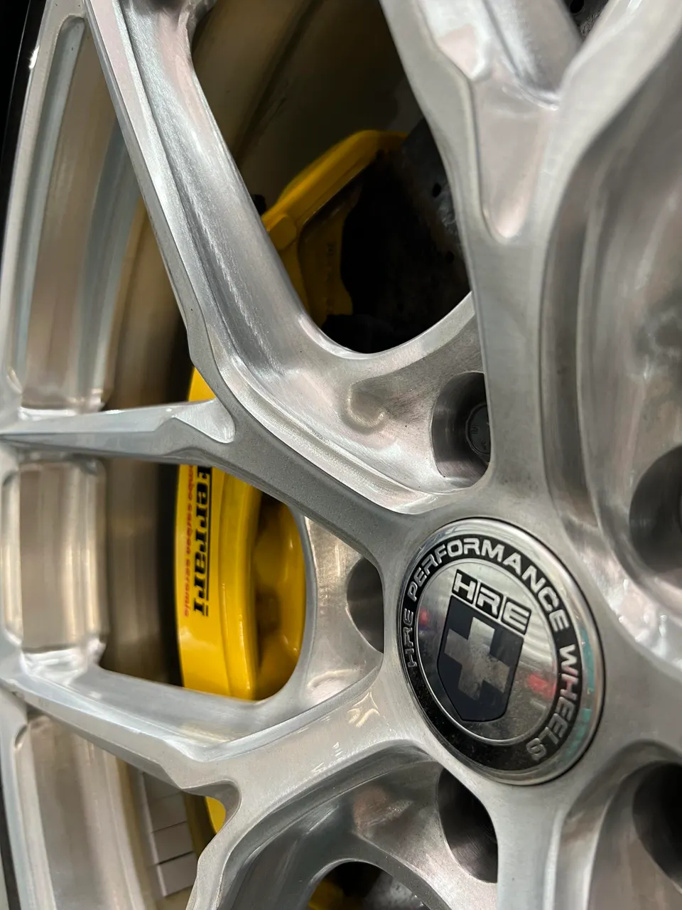 Close-up of a silver HRE performance wheel with yellow Ferrari carbon ceramic brake calipers.