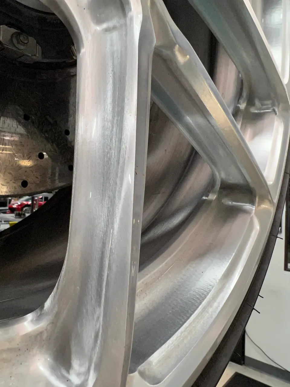 Close-up of a silver multi-spoke performance wheel and a drilled brake rotor on a high-performance car.
