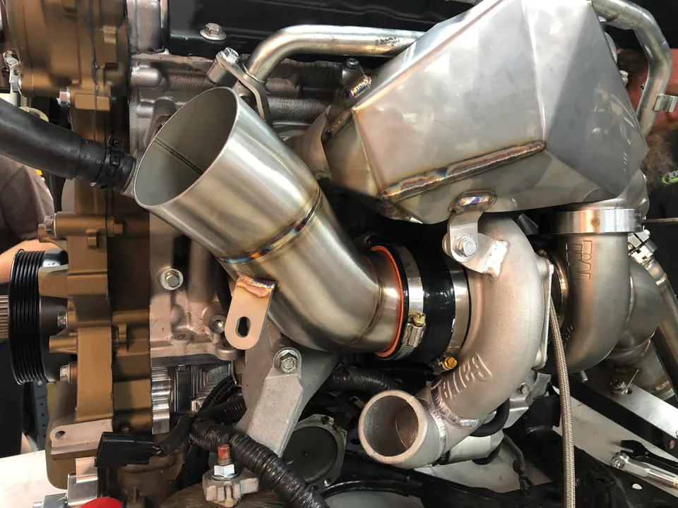 Close-up of a high-performance engine featuring a large turbocharger and custom boost piping during assembly.
