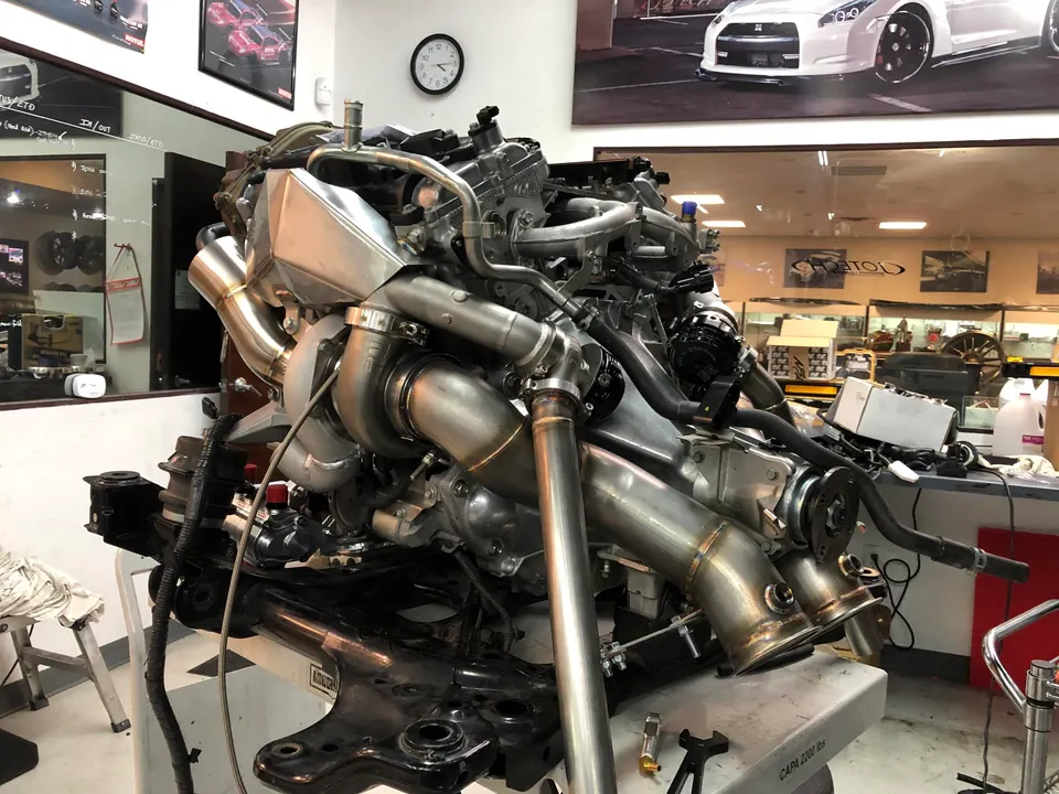VR38DETT engine with twin turbochargers and custom exhaust downpipes being assembled at Jotech Motorsports shop.