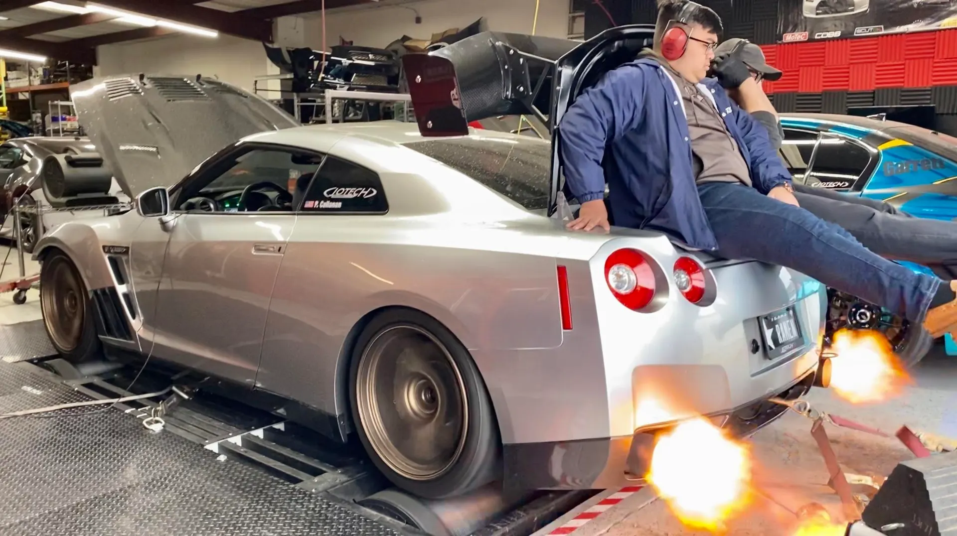 A silver Nissan GT-R on a dyno with exhaust flames, being tuned at Jotech Motorsports.