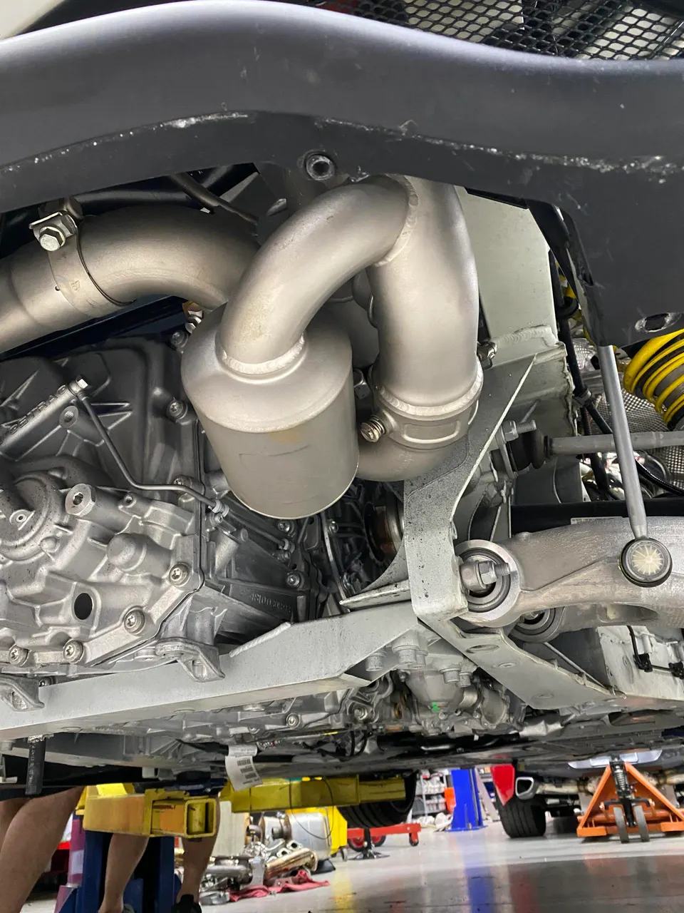Underside view of a performance car on a lift, showcasing the custom exhaust system, transmission, and suspension components.