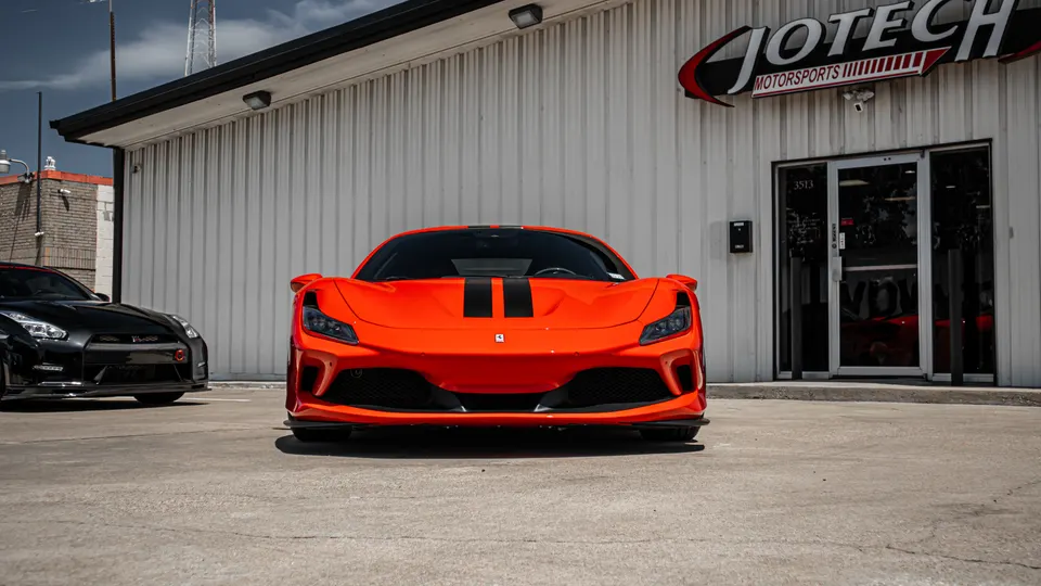 Orange Ferrari F8 Tributo and black Nissan GT-R parked outside Jotech Motorsports performance tuning shop.
