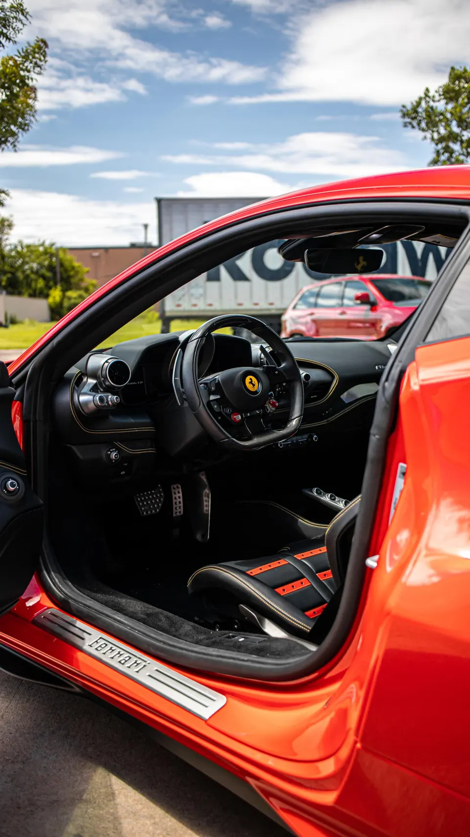 Close-up of a red Ferrari's luxurious interior, showcasing the steering wheel, dashboard, and black and red seats.