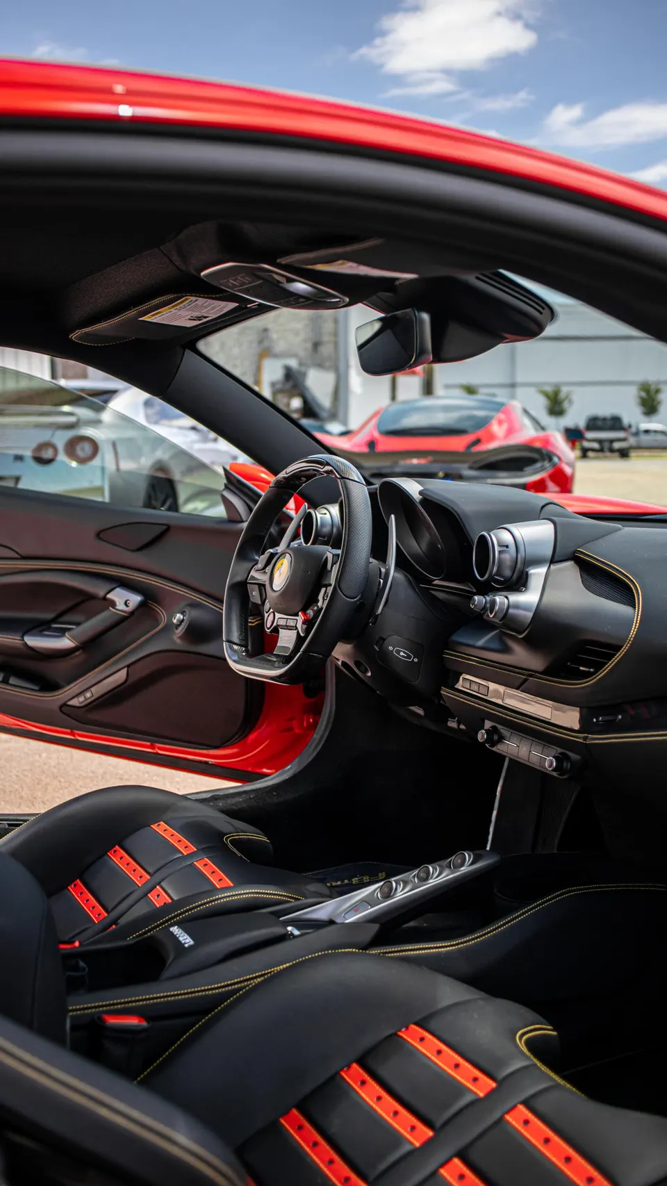 Interior view of a red Ferrari with black and red seats, showing the steering wheel and dashboard.