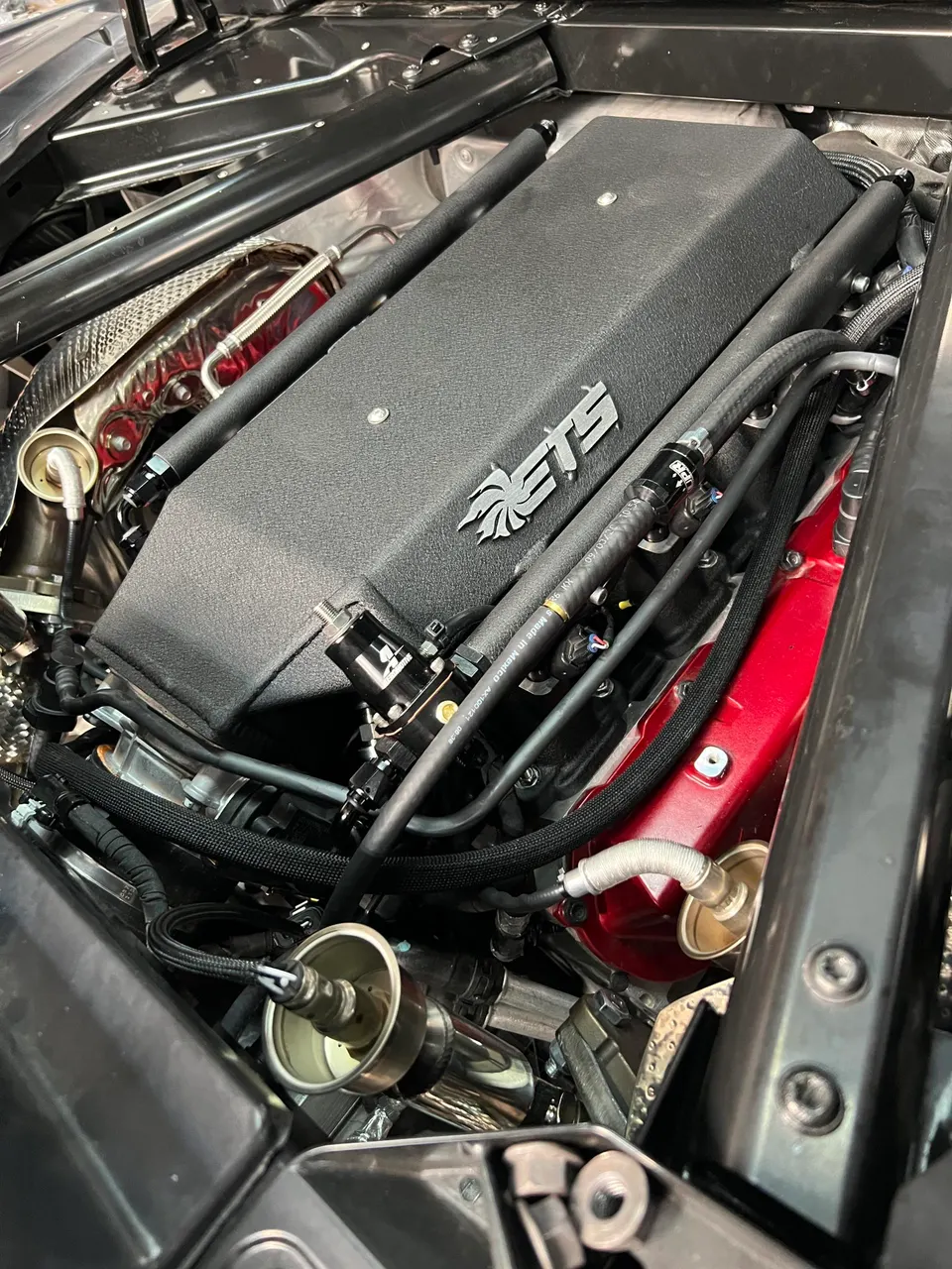 Close-up of a high-performance engine bay featuring an ETS intake manifold and custom fuel lines.
