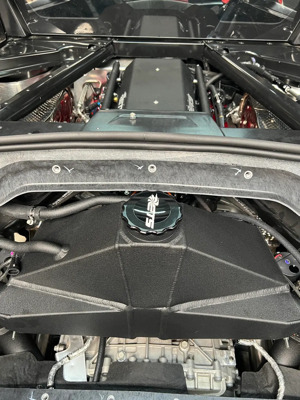 Close-up view of a high-performance engine bay featuring an aftermarket intake manifold and custom oil cap.