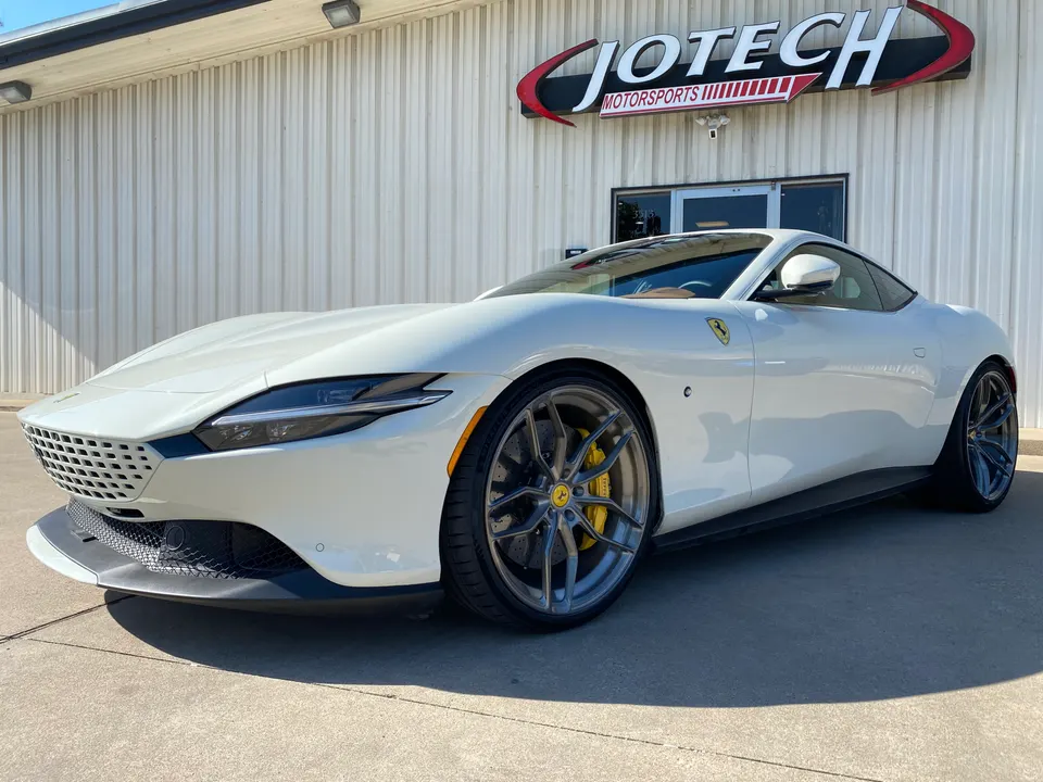 A white Ferrari Roma with custom wheels parked outside Jotech Motorsports.