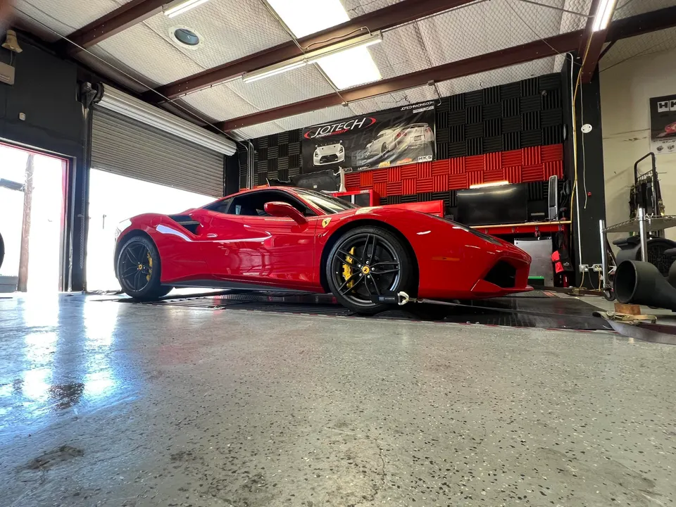 A red Ferrari sports car strapped to a dynamometer for performance tuning at Jotech Motorsports.
