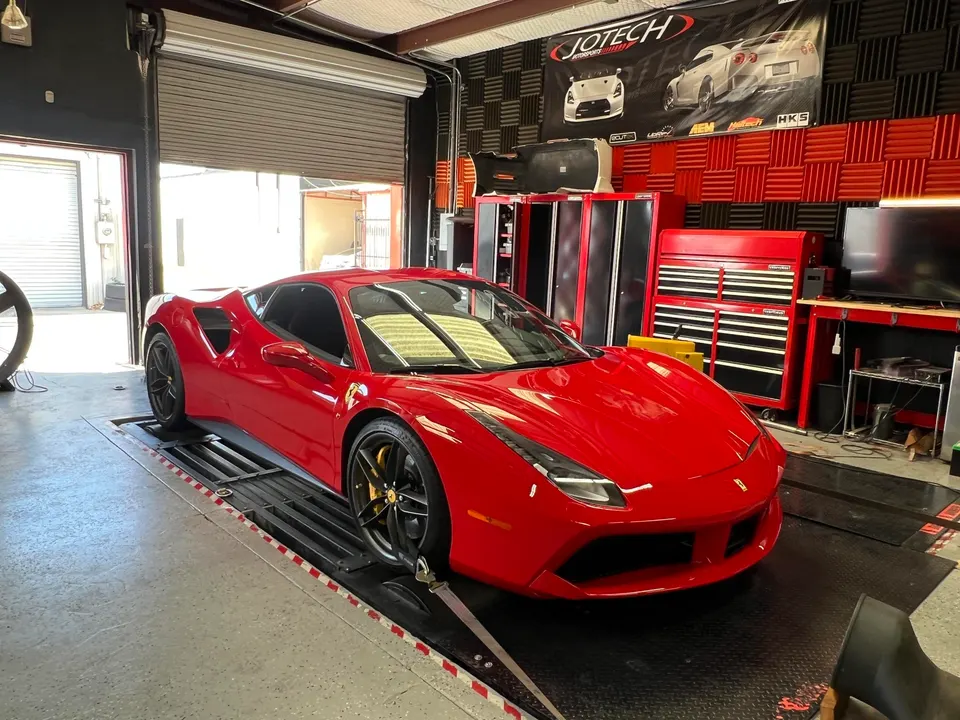 Red Ferrari 488 strapped to a dyno at Jotech Motorsports for performance tuning.
