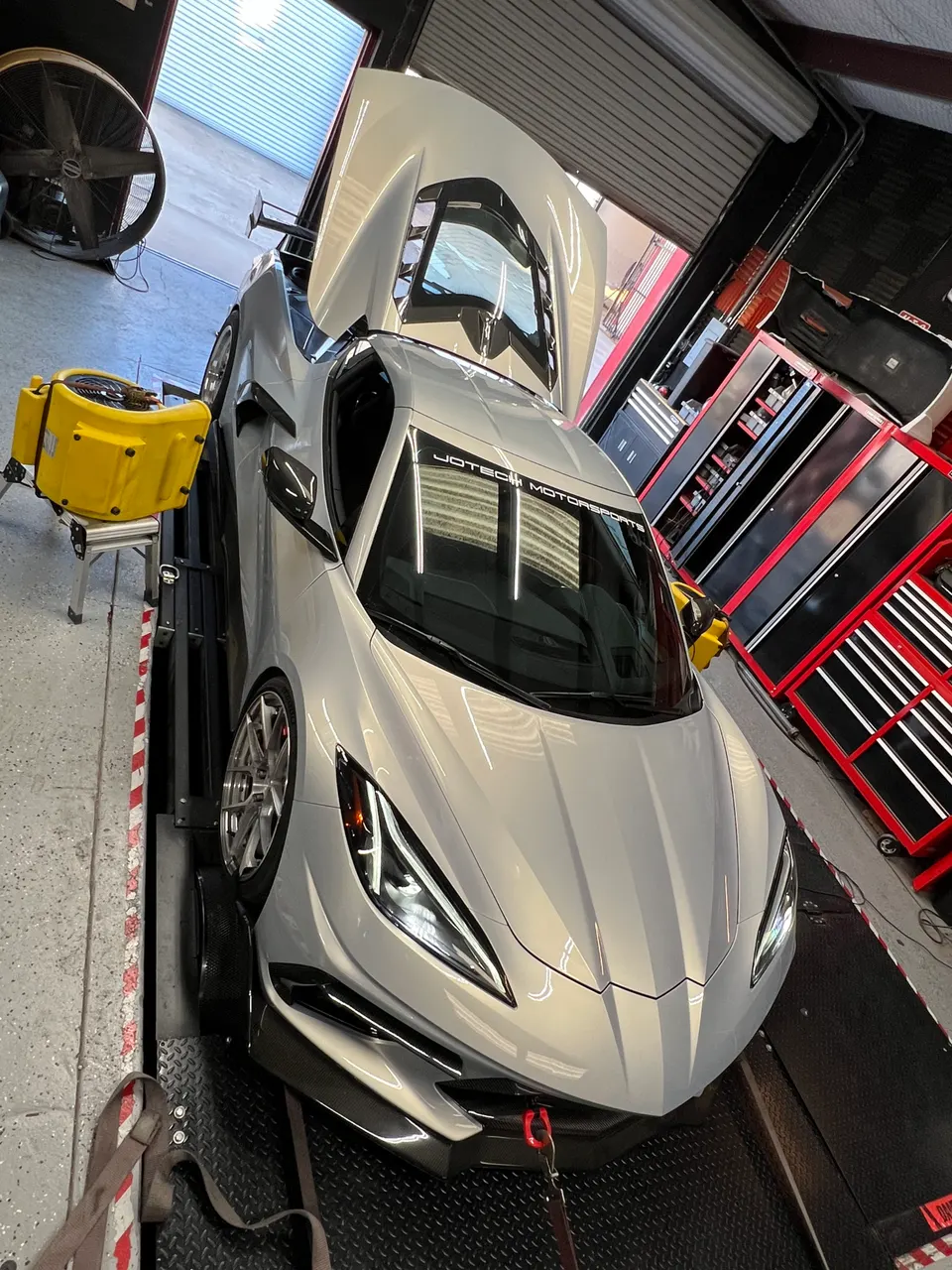 A silver C8 Corvette on a dyno at Jotech Motorsports for performance tuning and horsepower measurement.
