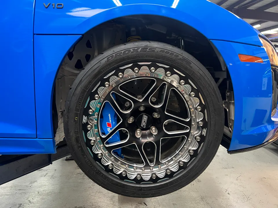 Blue Audi R8 V10 with custom black and chrome wheels, Toyo Proxes R888R tires, and blue Audi ceramic brake calipers.