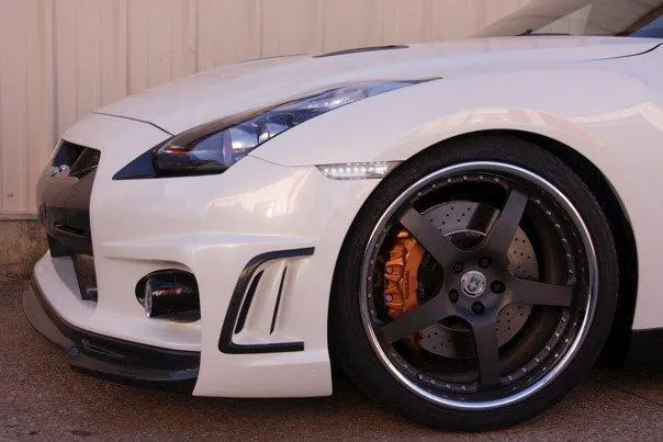 White Nissan GT-R with custom multi-spoke wheels, large orange brake calipers, and drilled rotors.