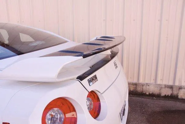 Rear view of a white Nissan GT-R showcasing an aftermarket carbon fiber wing and HKS badging.