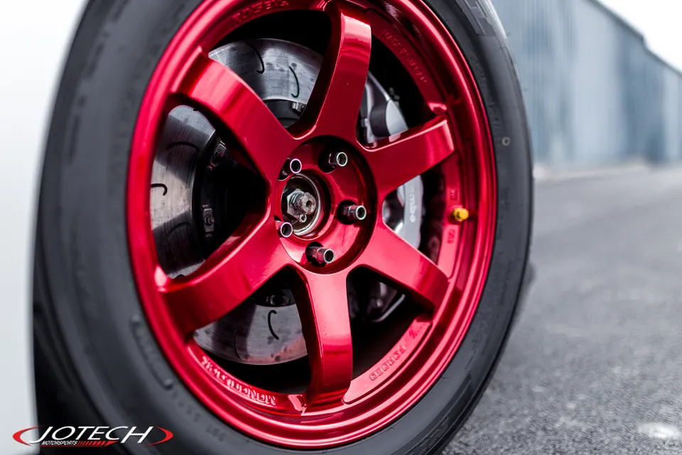 Close-up of a red forged wheel with Brembo brakes and slotted rotors on a performance car.