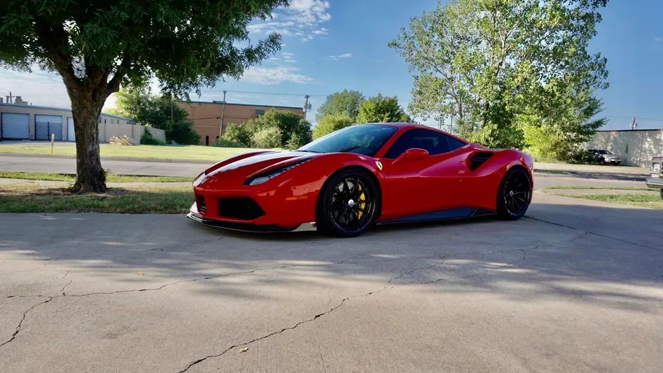 A red Ferrari 488 parked outdoors on a sunny day, showcasing its sleek design and black wheels with yellow calipers.