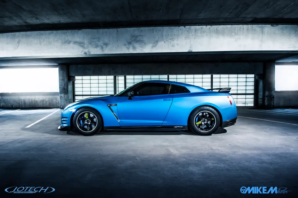 Blue Nissan GT-R R35 parked in a concrete garage, showcasing its side profile and custom wheels.