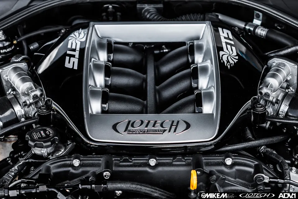 A close-up view of a Jotech and ETS branded performance intake manifold in a car's engine bay.