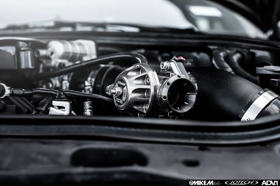 A close-up shot of a GReddy blow-off valve installed in a high-performance car's engine bay.