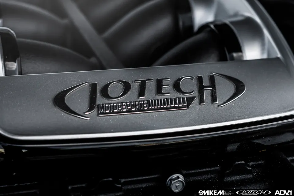 Close-up of a Jotech Motorsports branded intake manifold or engine cover in a high-performance car's engine bay.