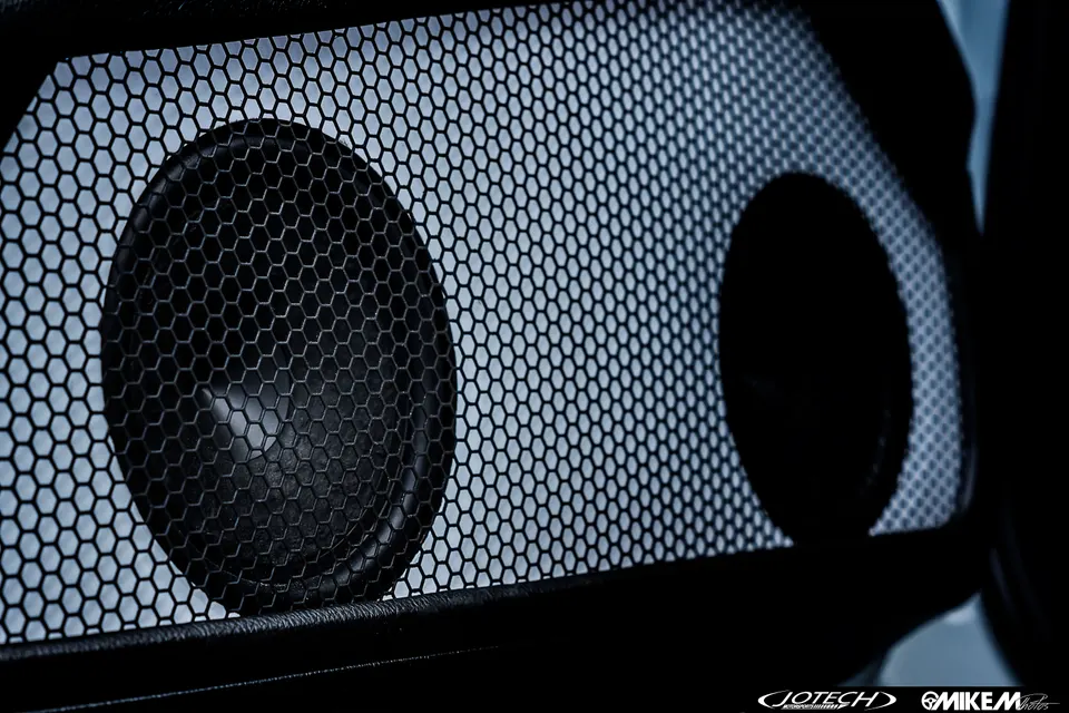 Close-up of a car's interior speaker with a honeycomb grille, part of a custom audio system.