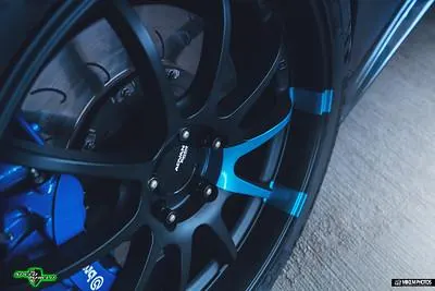 A close-up of a car's black Advan wheels with blue brake calipers and slotted rotors.