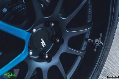 Close-up of a black Advan Racing wheel with a blue brake caliper and Speedshield tire valve cap.