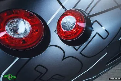 Close-up of a Nissan GT-R's custom wrapped rear with illuminated circular taillights and graphic design.