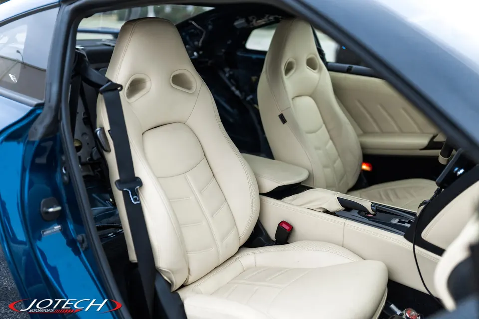 Close-up of a Nissan GT-R's beige leather interior, showing the front bucket seats and center console.