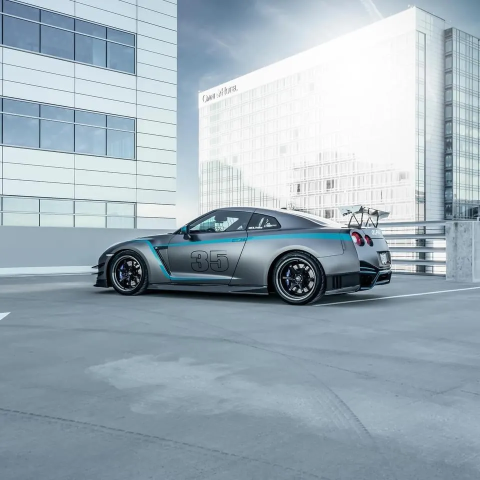 A grey Nissan GT-R with blue racing stripes and the number 35 on its side, parked in a modern parking garage.