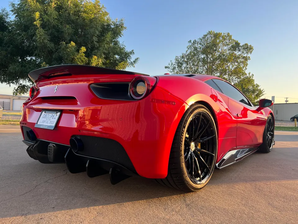 Red Ferrari 488 with aftermarket wheels, carbon fiber rear diffuser, and spoiler parked outdoors.