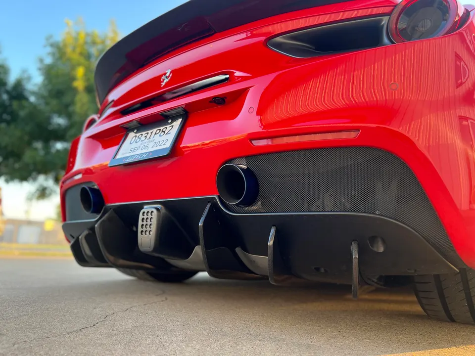 Rear view of a red Ferrari 488 showcasing aftermarket exhaust tips, carbon fiber diffuser, and rear spoiler.