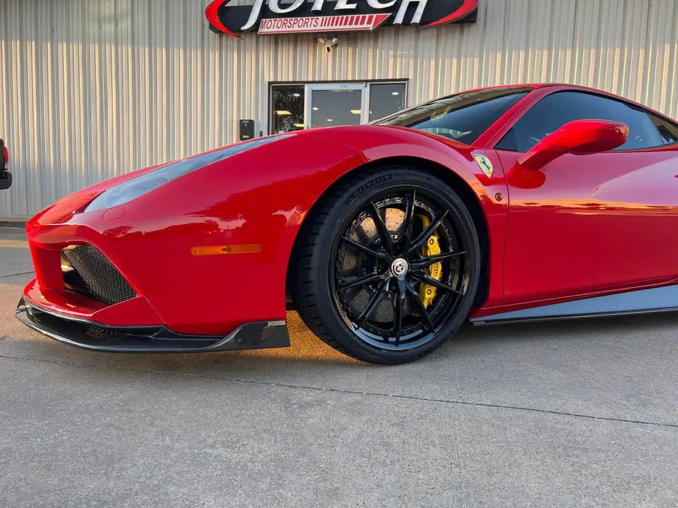Red Ferrari 488 with black aftermarket wheels, yellow brake calipers, and a carbon fiber front splitter parked outside Jotech Motorsports.