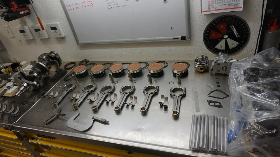 Engine internals laid out on a workbench, including pistons, connecting rods, and crankshaft, ready for assembly.