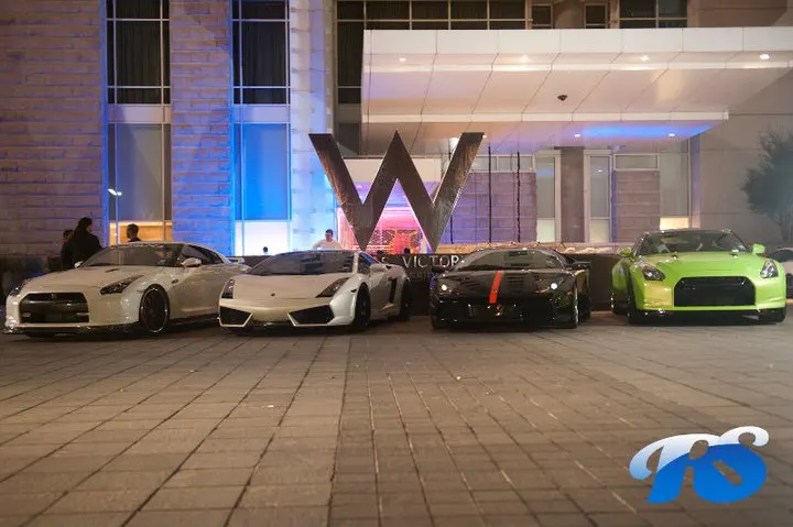 Four high-performance sports cars, including two Nissan GT-Rs and a Lamborghini Gallardo, parked in front of a W Hotel at night.