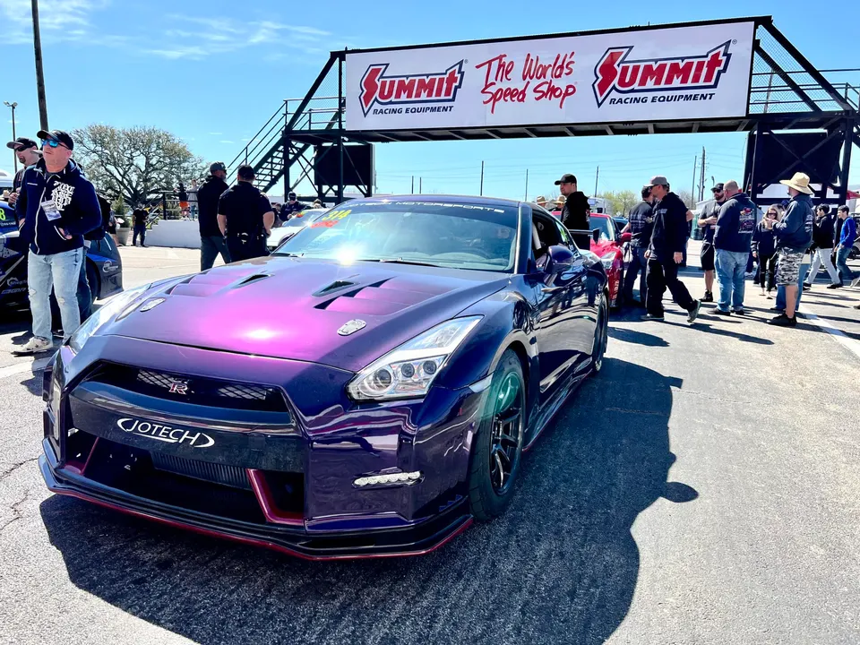 A purple Nissan GT-R with Jotech branding parked at a Summit Racing drag strip event under a clear sky.