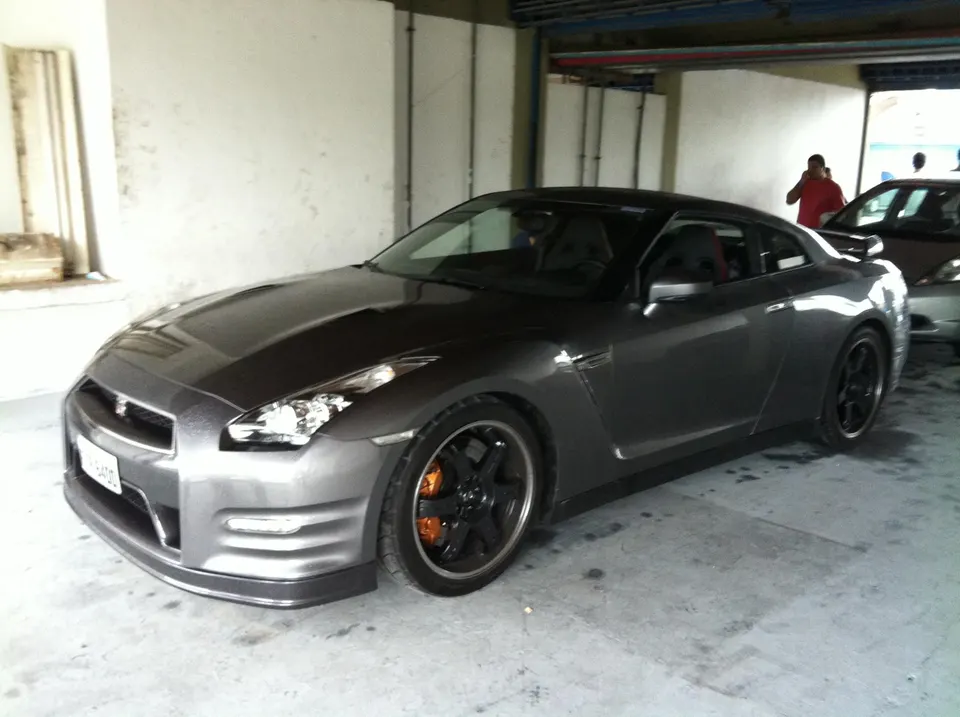 A grey Nissan GT-R R35 with orange brake calipers parked in a garage.