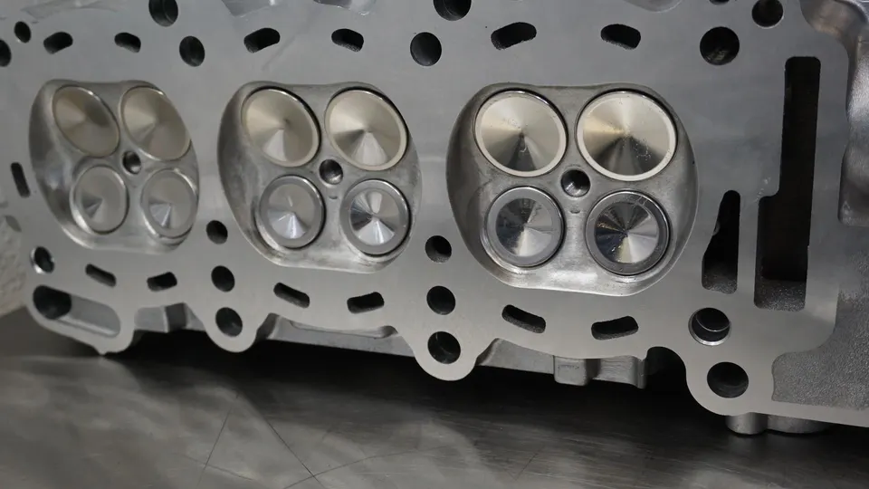 A close-up view of a performance engine cylinder head with multiple valves, showcasing precision engineering.