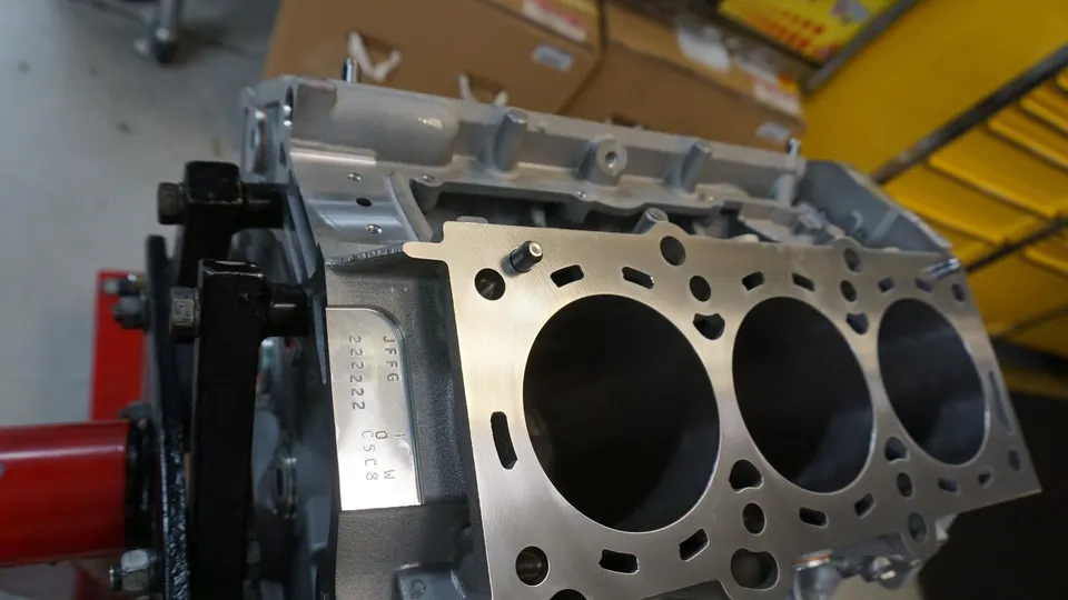 Close-up of an engine block on an engine stand in a performance tuning shop, showing cylinder bores and head surface.