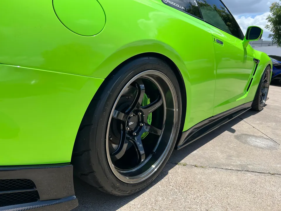 Close-up of a lime green Nissan GT-R's rear wheel, featuring Advan wheels and Brembo brakes.